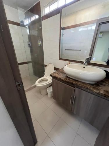 a bathroom with a sink and a toilet and a mirror at Aparta Suites La Flora- Infinity Living in Cali