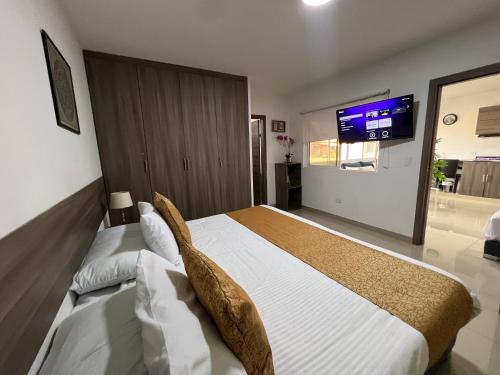 a bedroom with a large bed with a tv on the wall at Aparta Suites La Flora- Infinity Living in Cali