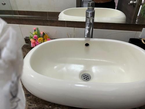 a white sink in a bathroom with flowers on a counter at Aparta Suites La Flora- Infinity Living in Cali