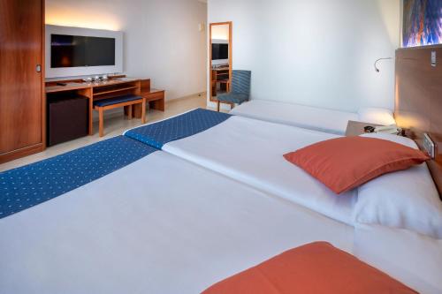 a large white bed in a room with a desk at GHT S'Agaró Mar Hotel in Sant Feliu de Guixols