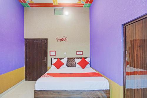 a bedroom with a bed with purple and red pillows at Hotel O Dwarka in Alīgarh