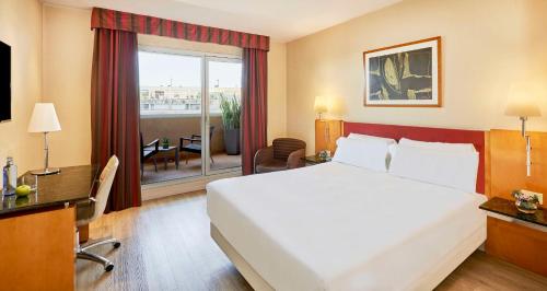 a hotel room with a large bed and a balcony at NH Ciutat de Reus in Reus
