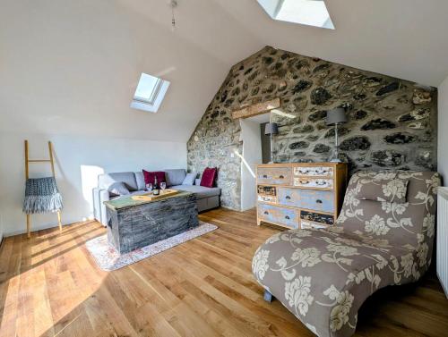 a living room with a couch and a stone wall at Ty Isaf Welsh Farmhouse with Sea Views in Llanddwywe