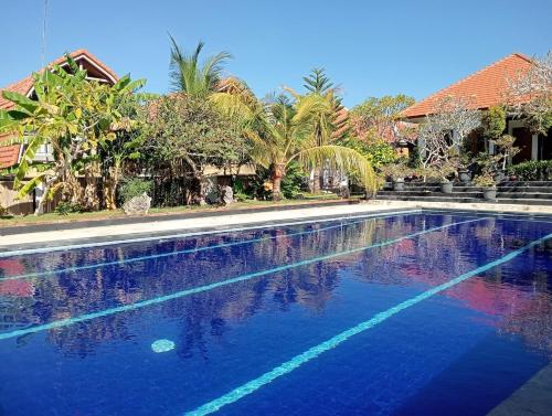 a swimming pool with blue water and palm trees at Villa Lumbung Uluwatu 2 in Uluwatu