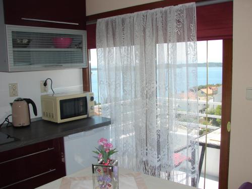 a kitchen with a microwave and a window with a view at Apartments Špiko in Hvar