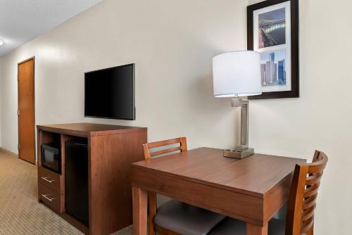 a room with a desk with a television and a table with a lamp at Comfort Inn & Suites in Taylor