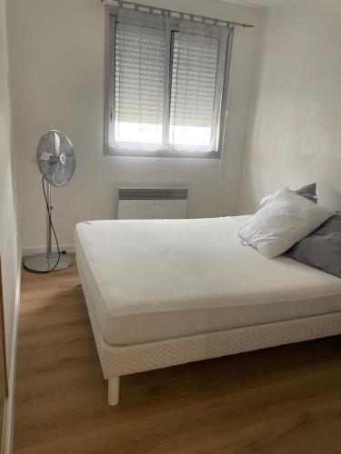 ein weißes Bett in einem Schlafzimmer mit einem Fenster in der Unterkunft Plage des quilles in Sète