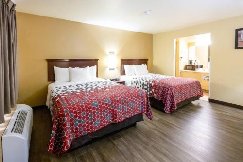 a hotel room with two beds with red sheets at Econo Lodge McAlester in McAlester