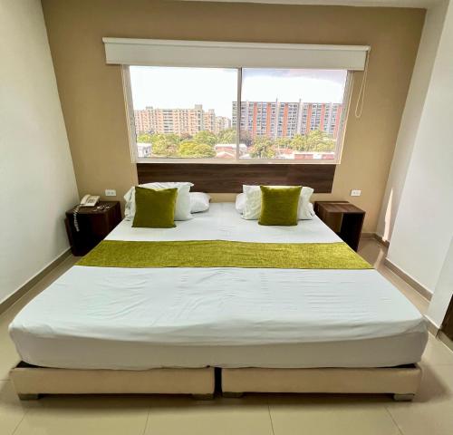 a large bed in a room with a large window at Aparta Suites La Flora- Infinity Living in Cali