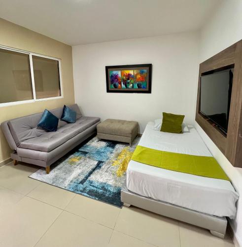 a bedroom with a bed and a couch and a tv at Aparta Suites La Flora- Infinity Living in Cali