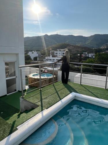 a woman sitting on a balcony looking at a swimming pool at Aparta Suites La Flora- Infinity Living in Cali