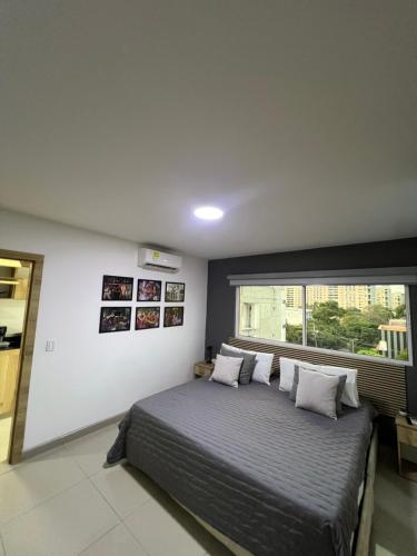 a bedroom with a large bed and a window at Aparta Suites La Flora- Infinity Living in Cali