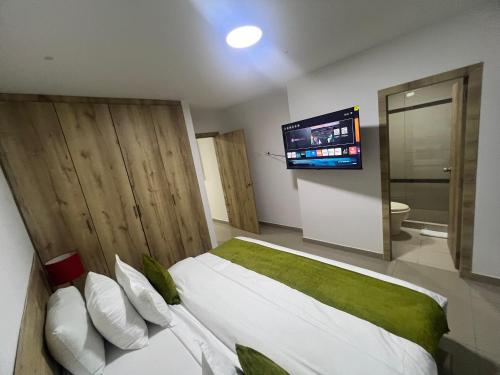 a bedroom with a bed with a tv on the wall at Aparta Suites La Flora- Infinity Living in Cali