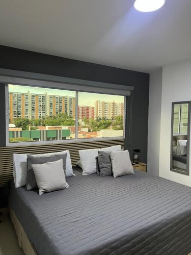 a bedroom with a large bed with a large window at Aparta Suites La Flora- Infinity Living in Cali