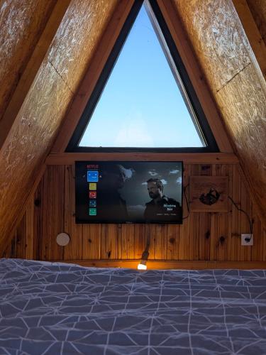 a tv in a room with a window at A Pine vikendica u srcu Zapadne Srbije in Nova Varoš