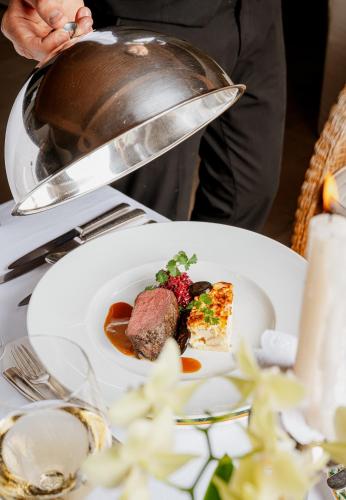 a person holding a pan over a plate of food at Hotel Mignon Meran Park & Spa in Merano