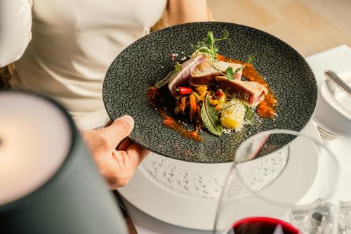 a person holding a plate of food on a table at Hotel Mignon Meran Park & Spa in Merano