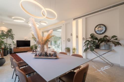 a dining room with a table with chairs and a clock at Olga Resort - אולגה ריזורט in H̱adera