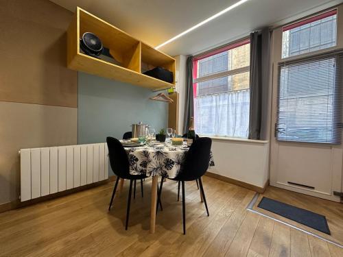 a dining room with a table and black chairs at S Le Cocon des Francs Studio Élégant centre ville in Sedan