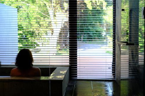 a woman sitting in a bath tub in front of a window at farm and bed SETODA in Onomichi