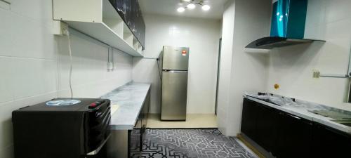 a small kitchen with a refrigerator and a counter at Diplomatik Homestay Alam Desa Presint 15 Putrajaya in Putrajaya