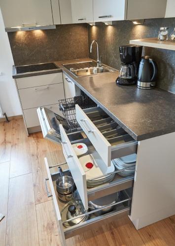 a kitchen with a sink and an open dishwasher at Appartements Der Fuchsbau in Saalbach Hinterglemm