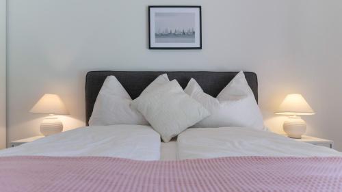 a bedroom with a bed with white pillows and two lamps at Cottage am See - Your Austrian Home in Mondsee
