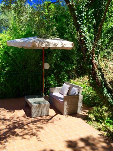 a patio with an umbrella and a couch and a table at Villa Emma Malcesine in Malcesine