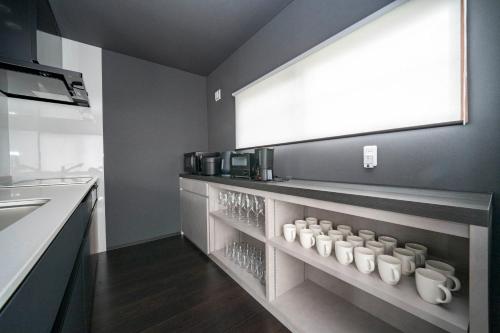 a kitchen with white coffee mugs on a shelf at Violet Garden in Furano