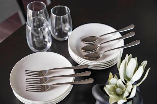 a black table with white plates and forks and glasses at Violet Garden in Furano
