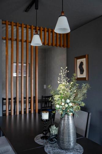 a dining room table with a vase of flowers on it at Violet Garden in Furano