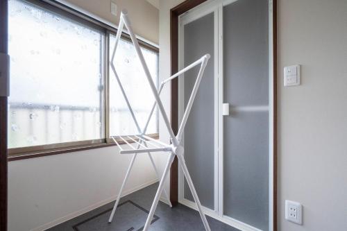 a white tripod in a room with a window at Violet Garden in Furano