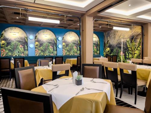 een restaurant met tafels en stoelen en een muur met palmbomen bij A-ONE Bangkok Hotel in Bangkok