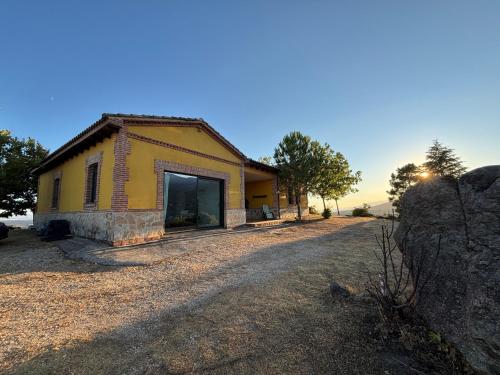 a small yellow house with a large window at El Encuentro - Casa Rural - in Arenas de San Pedro