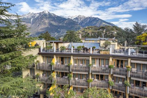 a hotel with mountains in the background at Hotel Mignon Meran Park & Spa in Merano