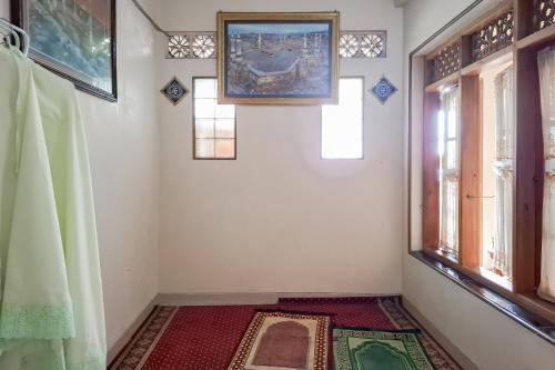 a room with a rug on the floor and windows at RedDoorz Hotel Tejomoyo Near Bukit Sekipan Tawangmangu in Tawangmangu