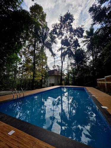 a blue swimming pool with trees in the background at Swasta Homestays Wayanad in Kaniyāmbetta