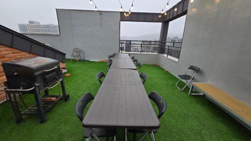 a long table with chairs and a grill on a balcony at A Bridge House 1C-1 in Jung-gu