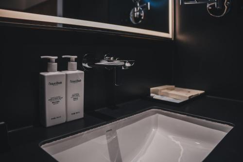 a bathroom sink with two white bottles on a black counter at PingYao Chengfu Jinyuan Hotel in Pingyao