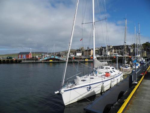 a white sailboat docked at a dock in the water at Eddlewood Guest House in Lerwick