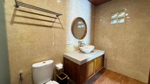 a bathroom with a toilet and a sink and a mirror at Ubud Kerta Prashati in Ubud