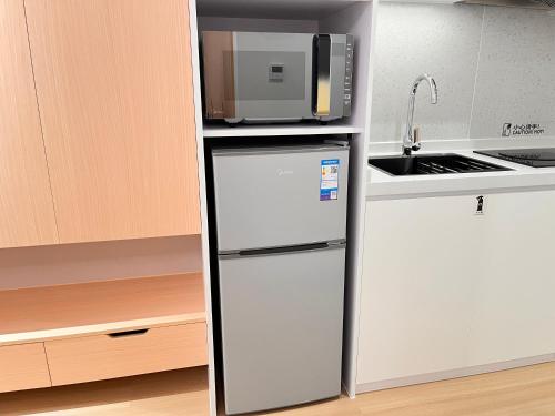 a white refrigerator in a kitchen with a microwave at Citadines Gongbei Zhuhai in Zhuhai