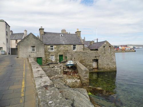 an old stone building in the water next to a dock at Eddlewood Guest House in Lerwick