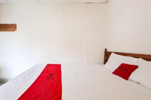 a bedroom with a white bed with red sheets and pillows at RedDoorz Hotel Tejomoyo Near Bukit Sekipan Tawangmangu in Tawangmangu