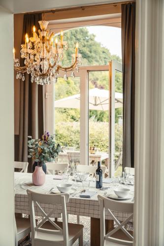 a dining table with white chairs and a chandelier at Villa Louise in Durbuy