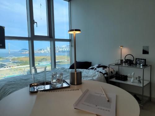 a room with a bed and a desk with a table with a lamp at Busan Station KTX 30s Ocean View 부산역ktx 30초 오션뷰 in Busan
