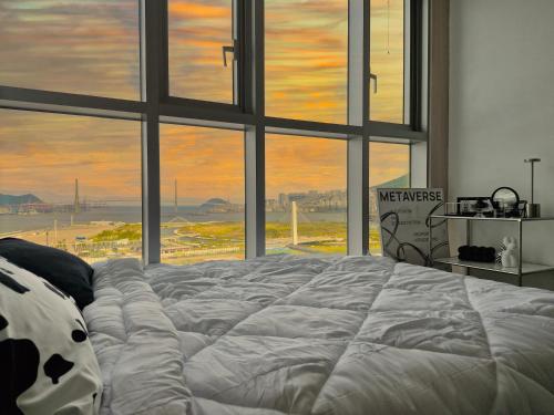 a large bed in a room with a large window at Busan Station KTX 30s Ocean View 부산역ktx 30초 오션뷰 in Busan