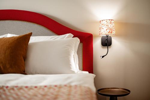 a bed with a red headboard and a lamp on a wall at Castel Sallegg Suites Adults only in Caldaro