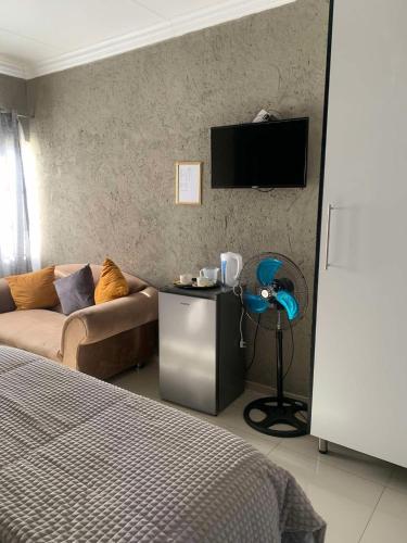 ein Schlafzimmer mit einem Sofa und einem TV an der Wand in der Unterkunft Ivy B&B Guest House in Nelspruit