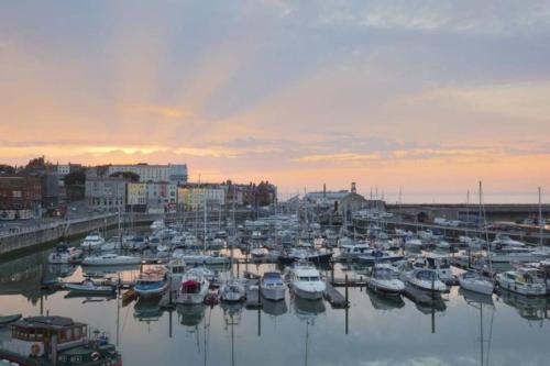a group of boats docked in a harbor at sunset at Alma Cottage - 17th Century Flint Cottage in Ramsgate